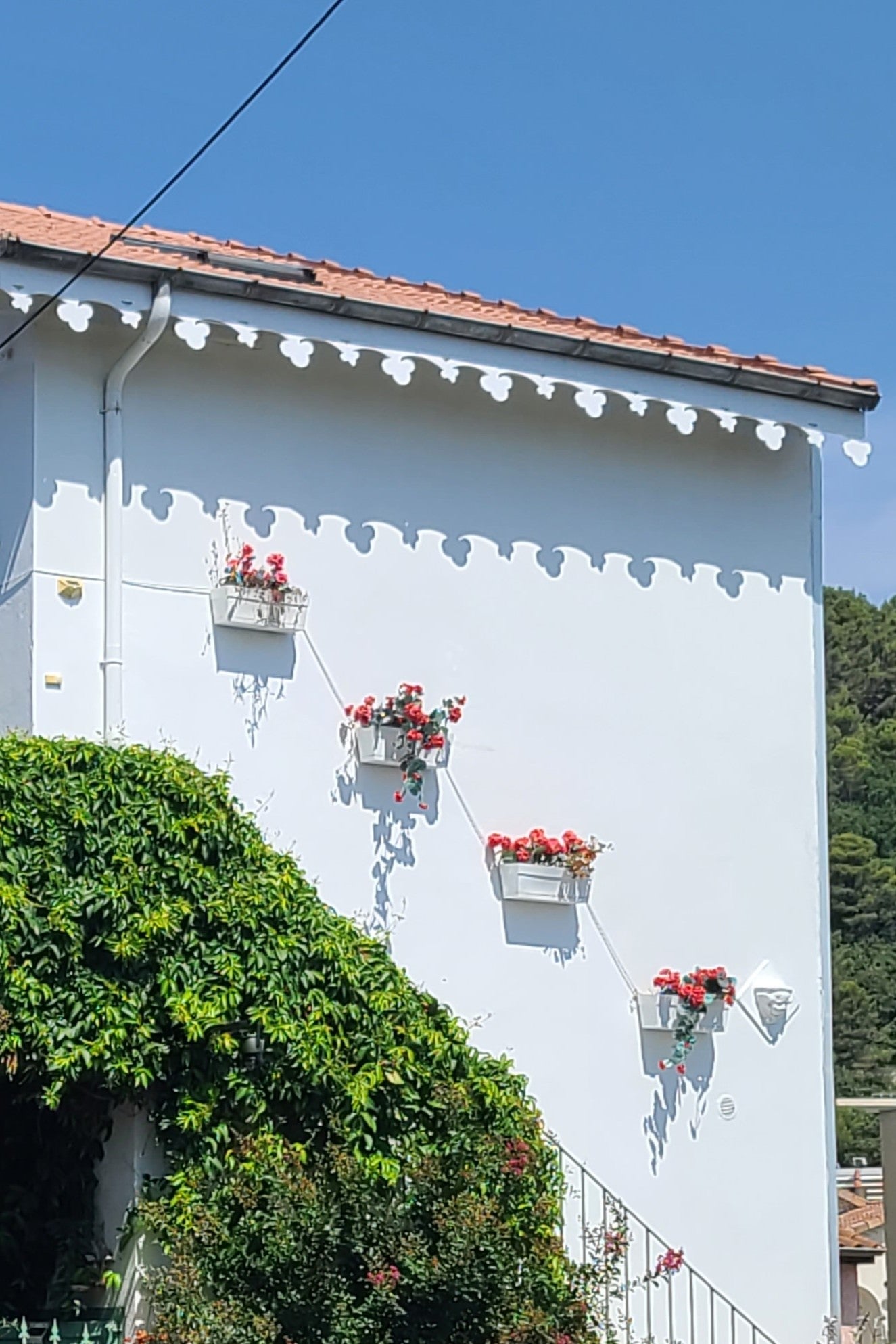 Lambrequin de toit sur maison fleurie, modèle LES-DALLES en PVC blanc, ORNABAT